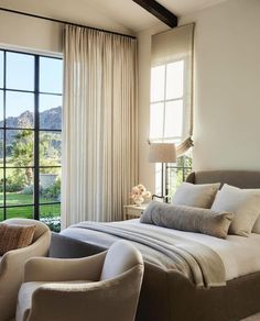 a bedroom with a large bed and two chairs in front of the sliding glass doors