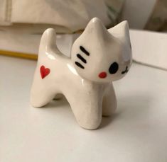 a white cat figurine sitting on top of a table next to a pillow