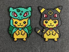 two pixelated pokemon brooches sitting on top of a gray cloth covered surface