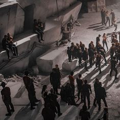 a group of people standing around each other in the middle of a dirt area with stairs