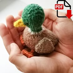 a hand holding a small knitted bird in it's right hand with an arrow pointing to the left