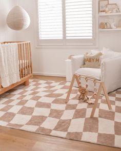 a baby's room with a checkered rug, rocking chair and crib