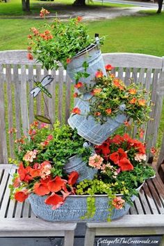 two buckets filled with flowers sitting on top of a wooden bench