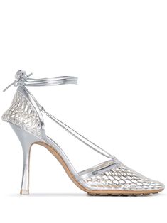 Silver-tone leather Stretch 90mm metallic sandals from BOTTEGA VENETA featuring metallic finish, mesh detailing, square toe, tie-fastening ankle strap, high stiletto heel and branded leather insole. Designer Silver Fitted Heels, Silver Bottega Bag, Luxury Metallic Silver Leather Heels, Silver Heels Farfetch, Luxury Heels With Silver-tone Hardware, Ankle Strap, Silver Pumps, Designer Pumps