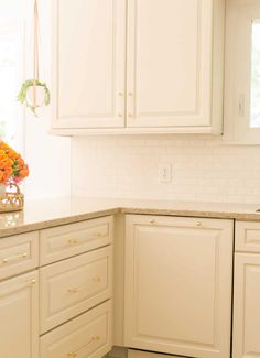 a kitchen with white cabinets and marble counter tops