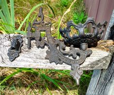 an old metal object is sitting on a piece of wood in front of some grass