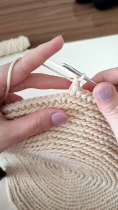 a woman is knitting a sweater with a crochet hook