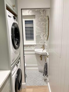 a washer and dryer in a small room with white walls, wood floors and flooring