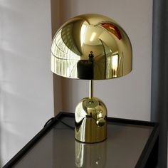 a shiny gold lamp sitting on top of a black table