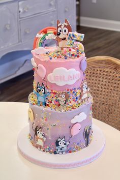 a three tiered cake is decorated with cartoon characters and rainbow sprinkles