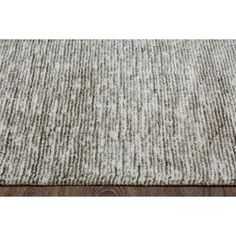 an area rug with white and brown stripes on the top, in front of a wooden floor