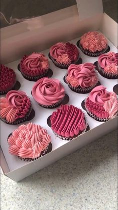 twelve cupcakes with pink frosting in a box