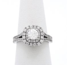 a white gold ring with an oval diamond surrounded by smaller round brilliant cut diamonds in the center