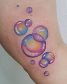 a colorful tattoo with bubbles on the side of someone's leg and foot,