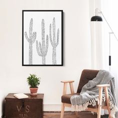 a living room with a chair, potted plant and framed art on the wall