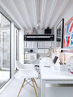 a white desk and chair in front of a window with bookshelves on the wall