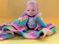 a baby doll sitting on top of a blanket