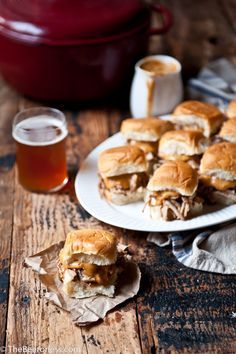 several sandwiches on plates next to a glass of beer and pot of stew in the background