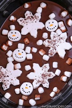 a crock pot filled with chocolate and marshmallows in the shape of snowmen