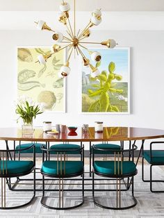 a dining room table with blue chairs and art on the wall