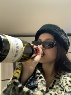 a woman drinking from a wine bottle while wearing sunglasses and a leopard print fur coat