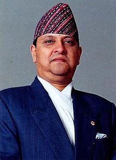 a man wearing a blue suit and tie with a red striped head scarf on his head