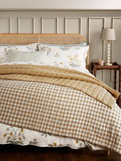 a bed with white and brown checkered comforter next to a night stand in a bedroom