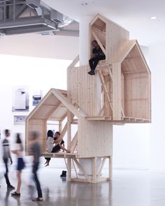 people are walking around an art exhibit with wooden structures on the floor and in the air