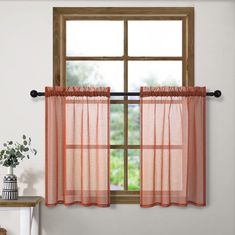 an open window with sheer curtains and a potted plant