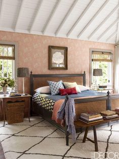 a bedroom with pink walls and white carpeted flooring has a large bed in the center