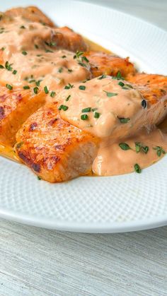 a white plate topped with meat covered in gravy on top of a wooden table