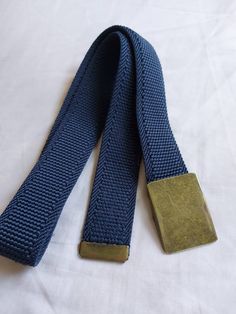 Classic boy's belt, adjustable with metal sliding buckle. Navy blue color. Model A (bronze buckle): Elastic band. Length 73 cm. Width 3 cm. Model B: Length 74 cm. Width 3 cm. Rigid tape (not elastic). Model C: Combined color of blue and orange lines. Length 83 cm. Width 3 cm. Rigid tape. Model D: Blue, white and yellow lines. Length 70 cm. Width 2.5 cm. Rigid tape. Boys Belt, Sports Belt, Navy Colour, Orange Line, Yellow Line, Webbing Belt, Suspender Belt, Navy Blue Color, Navy Color