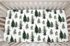 a white crib with green trees on it