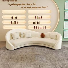 a curved white couch sitting in front of a wall with bottles on it's sides