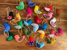 several colorful birds are hanging from string on a wooden table with wood planks in the background