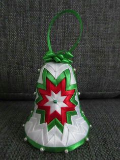 a white and green christmas bell ornament sitting on a couch