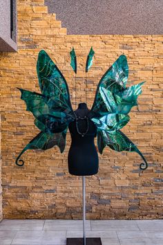 a mannequin is dressed up as a green leafy butterfly with long wings