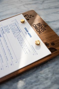 a wooden plaque with two gold buttons on it sitting on top of a marble table