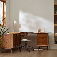 a wooden desk sitting next to a window with a clock on the top of it