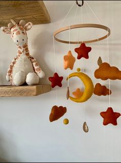 a stuffed giraffe sitting on top of a wooden shelf next to a mobile