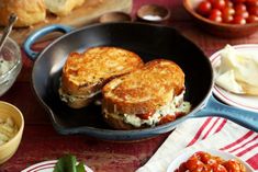 two grilled sandwiches in a cast iron skillet on a red and white tablecloth