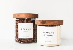 two jars filled with almonds sitting on top of a white counter next to each other