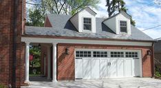 a brick house with two white garage doors