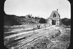 an old black and white photo of a dirt road with a house in the background