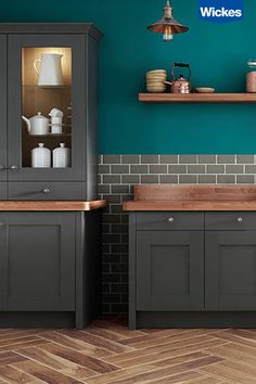 a kitchen with blue walls and wooden floors, cabinets in the center, and shelves on the other side