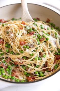 a pasta dish with peas, bacon and parmesan cheese in a skillet