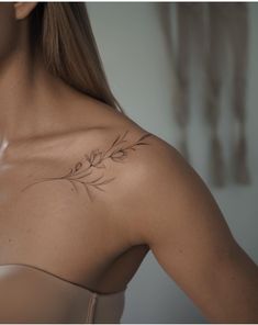 a woman with a tattoo on her chest and shoulder is looking down at the camera