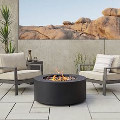 a fire pit sitting on top of a patio next to two chairs and a table