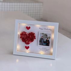 a white frame with red hearts and lights around it on top of a countertop