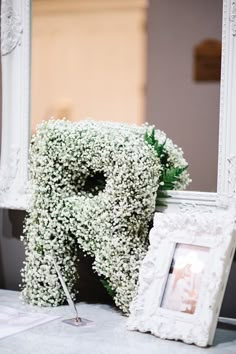 the letter p is made out of baby's breath flowers in front of a mirror